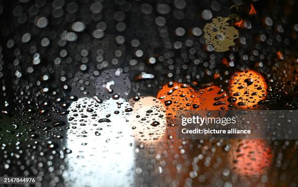 April 2024, Baden-Württemberg, Stuttgart: Lights from vehicles shine through a car windshield covered with raindrops. Photo: Bernd Weißbrod/dpa