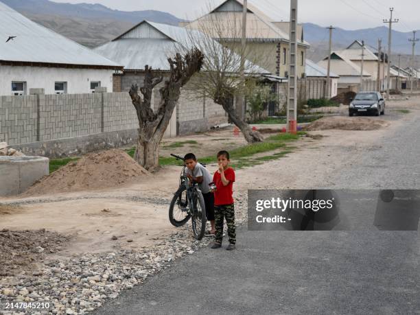 Two boys play on their bicycle along a road outside newly constructed homes in the village of Khuroson, near Obikiik, some 70 kilometers south of the...