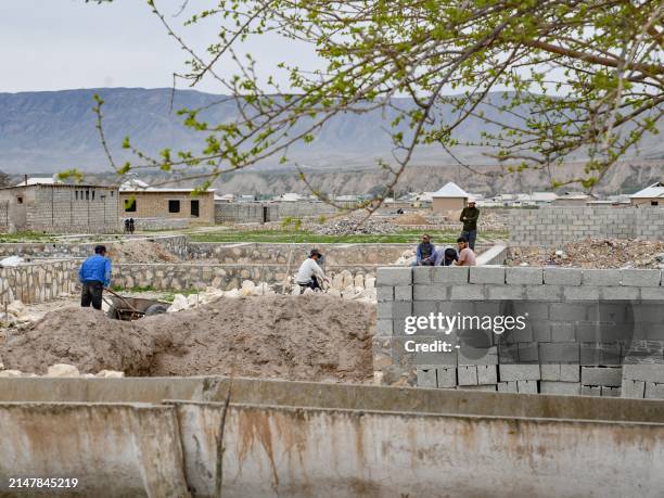 Men construct stone walls and buildings in the village of Khuroson, near Obikiik, some 70 kilometers south of the capital Dushanbe, on March 26,...