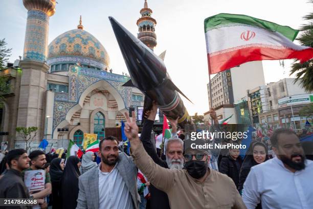 Unidentified men are carrying a model of Iran's first-ever hypersonic missile, Fattah, past a mosque during a gathering to celebrate the IRGC UAV and...