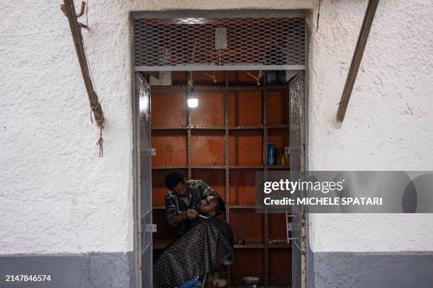 Barber shaves a customer's beard at a barbershop inside Harar walled city on April 15, 2024. Founded in the 10th century, Harar - also called Jugol -...