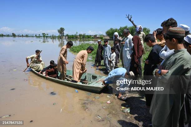 People arrive on a boat across a flooded area after heavy rains in Nowshera district, Khyber-Pakhtunkhwa province on April 16, 2024. At least 41...