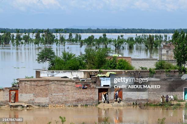 People stand at their deluged houses after heavy rains in Nowshera district, Khyber-Pakhtunkhwa province on April 16, 2024. At least 41 people have...