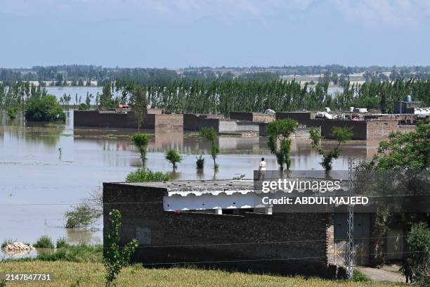Man stands on the roof of his deluged house after heavy rains in Nowshera district, Khyber-Pakhtunkhwa province on April 16, 2024. At least 41 people...