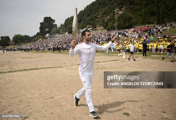 First torch bearer, rowing Olympic gold medalist on 2020, Stefanos Ntouskos, runs with the Olympic torch during the flame lighting ceremony for the...