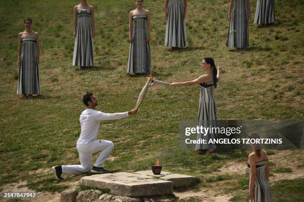 First torch bearer, rowing Olympic gold medalist on 2020, Stefanos Ntouskos receives the flame from Greek actress Mary Mina, playing the role of the...