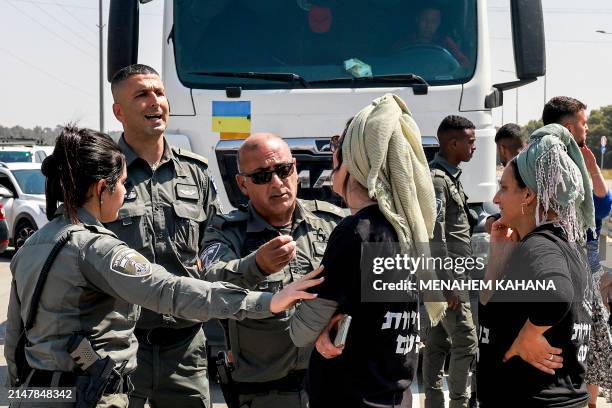 Israeli border guards talk to right-wing protesters blocking the road to Jordanian trucks carrying humanitarian aid supplies arriving on the Israeli...