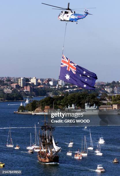 An Australian Navy helicopter hangs a large flag over the HM Bark Endeavour, a full scale replica of Captain James Cook's original 18th century ship,...