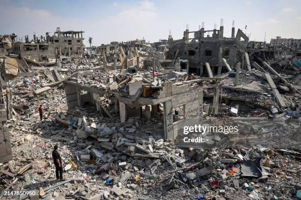 People inspect the damage amid the rubble of buildings destroyed during Israeli bombardment in Khan Yunis, on the southern Gaza Strip on April 16 as...