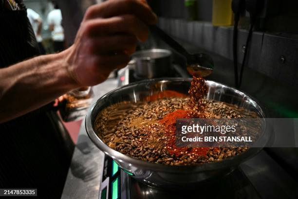 Sous chef Balazs Palko seasons crickets in the kitchen of the Yumbug edible insect restaurant in Finsbury Park, in London, on March 21, 2024. Yum...