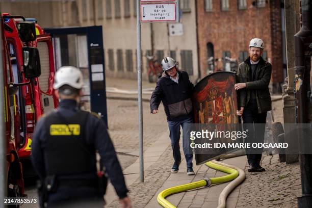Of Danish Business, Brian Mikkelsen , and CFO of Danish Business, Philip Werner Willerslev-Olsen, carry historical paintings out of the burning...