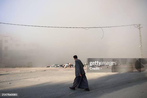 Man walks as smoke engulfs the area after Israeli bombardment at Al-Daraj neighbourhood in Gaza City on April 16 amid ongoing battles between Israel...