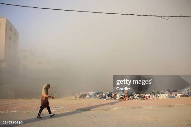 Woman walks as smoke engulfs the area after Israeli bombardment at Al-Daraj neighbourhood in Gaza City on April 16 amid ongoing battles between...