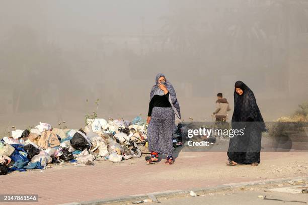 Women walk as smoke engulfs the area after Israeli bombardment at Al-Daraj neighbourhood in Gaza City on April 16 amid ongoing battles between Israel...