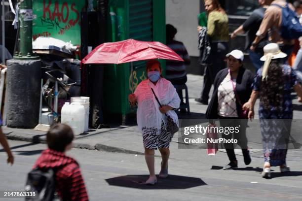Person is covering themselves from the sunlight with an umbrella on the streets of the Zócalo in Mexico City. The National Water Commission reports...