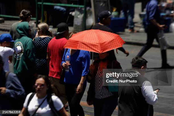 Person is covering themselves from the sunlight with an umbrella on the streets of the Zócalo in Mexico City. The National Water Commission reports...