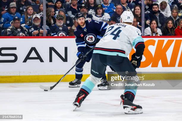 Gabriel Vilardi of the Winnipeg Jets plays the puck down the ice as Jamie Oleksiak of the Seattle Kraken defends during second period action at the...