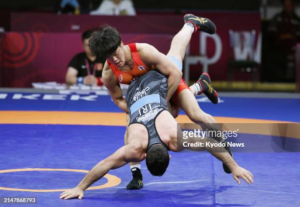 Taizo Yoshida of Japan competes against Rasoul Sadegh Garmsiri of Iran in the men's Greco-Roman 82-kilogram final at the Asian wrestling...