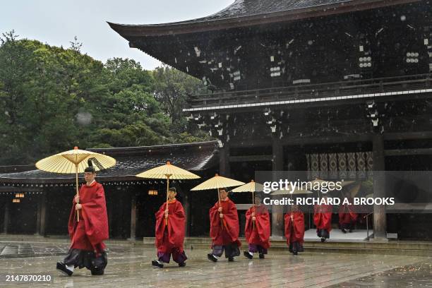 Shinto priests walk in procession on the grounds of Meiji Shrine before the arrival of members of Japan's imperial family to mark the 110th...