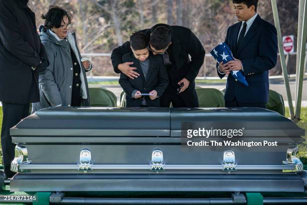 Arlington, VA Rosana Monge, her son Joseph, and grand children Joseph III, right, and Jax, center, stand at the casket of Joe Monge during a burial...