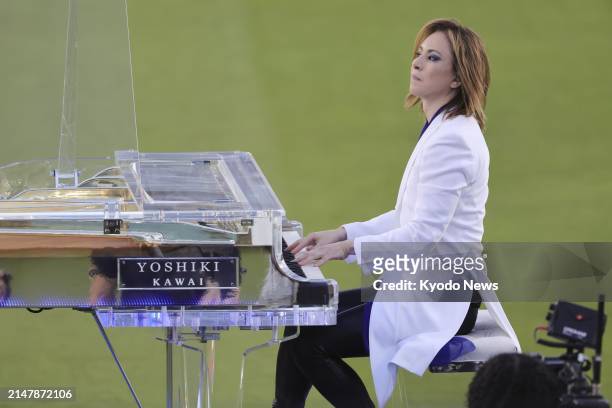 Japanese musician and songwriter Yoshiki performs in centerfield prior to the game between the Los Angeles Dodgers and the Washington Nationals at...
