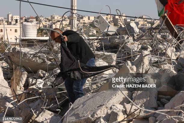 Villager walks over the rubble of the demolished house of a Palestinian man accused of participating in a deadly attack in the Israeli city of...