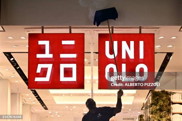 Worker cleans around the logo of the Fast Retailing clothing brand Uniqlo that will open tomorrow for the first ime in Rome, on April 17, 2024.