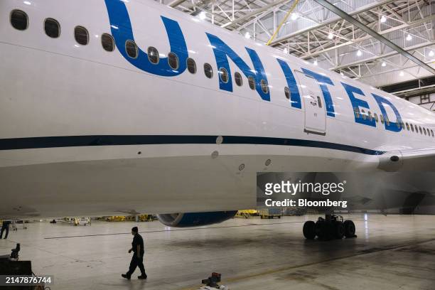 Worker walks under a Boeing 777-200 airplane in a United Airlines maintenance hangar at Newark Liberty International Airport in Newark, New Jersey,...