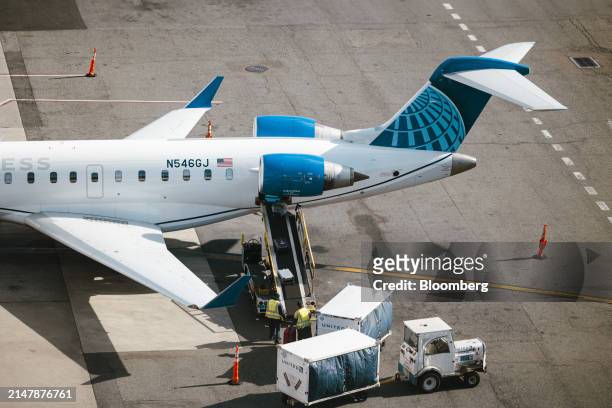 Workers load baggage onto a United Express CRJ-550 airplane at Newark Liberty International Airport in Newark, New Jersey, US, on Tuesday, March 19,...