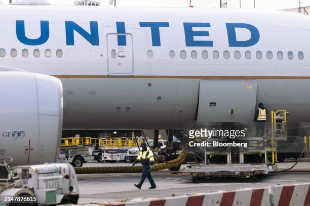 Worker walks past a United Airlines Boeing 777-200 airplane at a gate in Terminal C at Newark Liberty International Airport in Newark, New Jersey,...