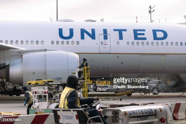 Workers in front of a United Airlines Boeing 777-200 airplane at a gate in Terminal C at Newark Liberty International Airport in Newark, New Jersey,...