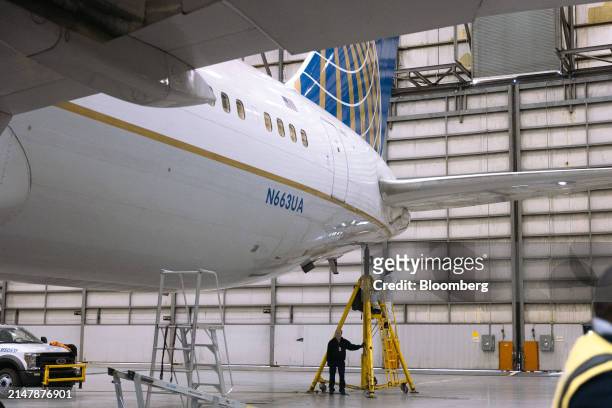 Workers lower jacks holding up a Boeing 767-300 airplane after servicing the landing gear in a United Airlines maintenance hanger at Newark Liberty...