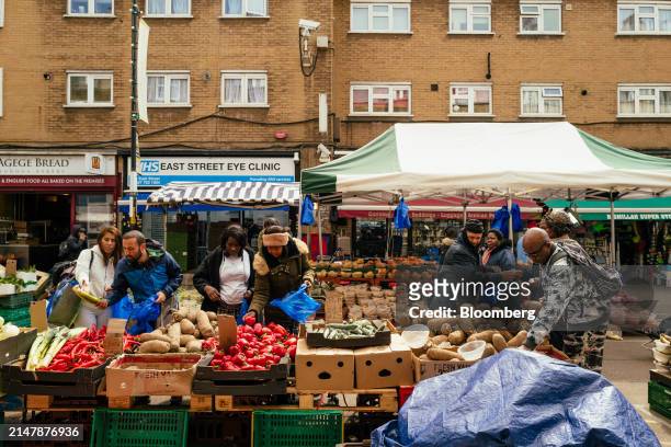 Shoppers pick fresh vegetables from a grocery stall at East Street Market in London, UK, on Wednesday, April 17, 2024. UK inflation slowed less than...