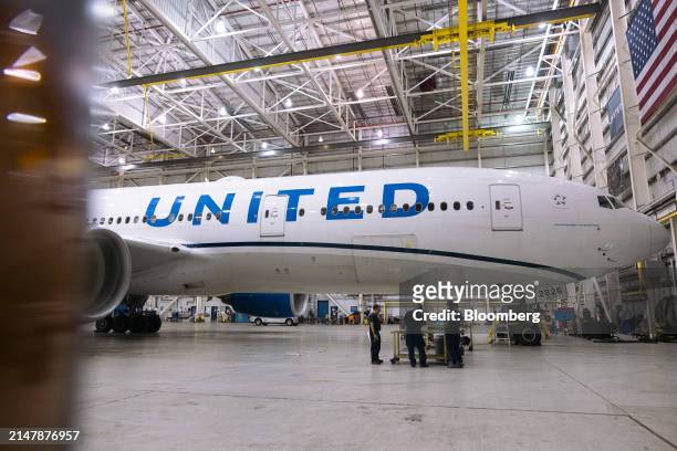 Workers replace an electrical cable on a Boeing 777-200 airplane in a United Airlines maintenance hangar at Newark Liberty International Airport in...