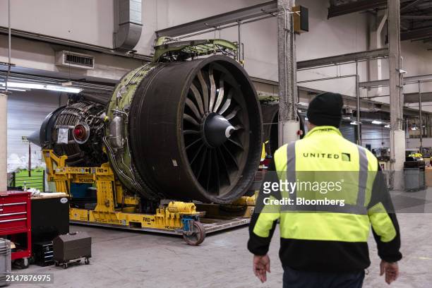 Worker walks past an engine for a Boeing 767 airplane in a United Airlines maintenance facility at Newark Liberty International Airport in Newark,...