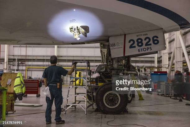 Worker shines a flashlight on a Boeing 777-200 airplane in a United Airlines maintenance hangar at Newark Liberty International Airport in Newark,...