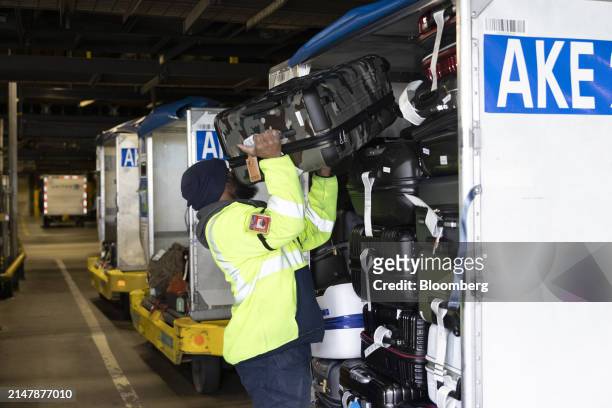 Ramp worker moves a piece of luggage in the Terminal C baggage room at Newark Liberty International Airport in Newark, New Jersey, US, on Tuesday,...