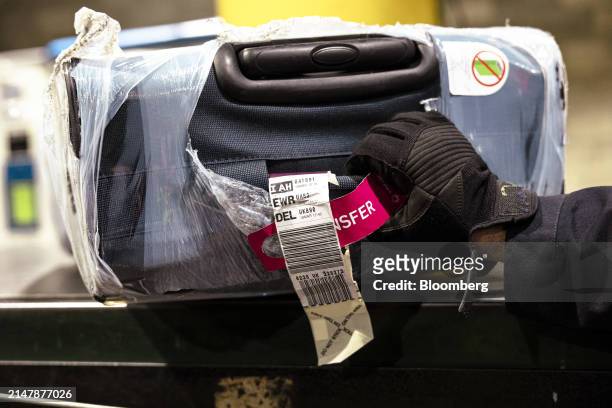 Ramp worker moves a piece of luggage in the Terminal C baggage room at Newark Liberty International Airport in Newark, New Jersey, US, on Tuesday,...