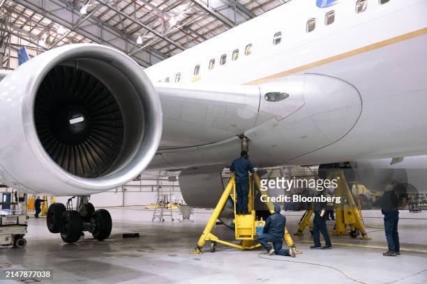 Workers lower jacks holding up a Boeing 767-300 airplane after servicing the landing gear in a United Airlines maintenance hanger at Newark Liberty...