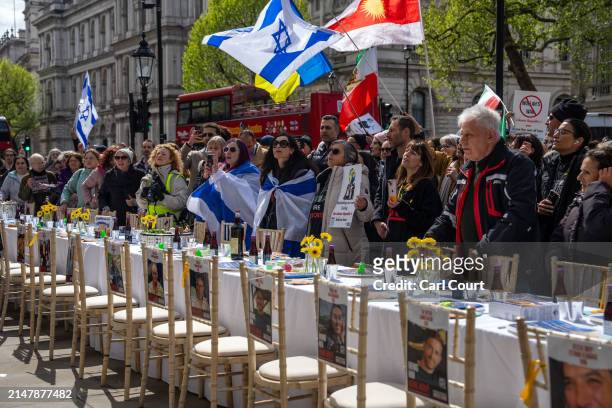 People gather around an empty seder table featuring 133 chairs representing the hostages taken by Hamas on October 7th, during a protest opposite...