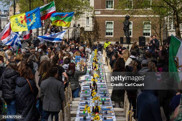 People gather around an empty seder table featuring 133 chairs representing the hostages taken by Hamas on October 7th, during a protest opposite...