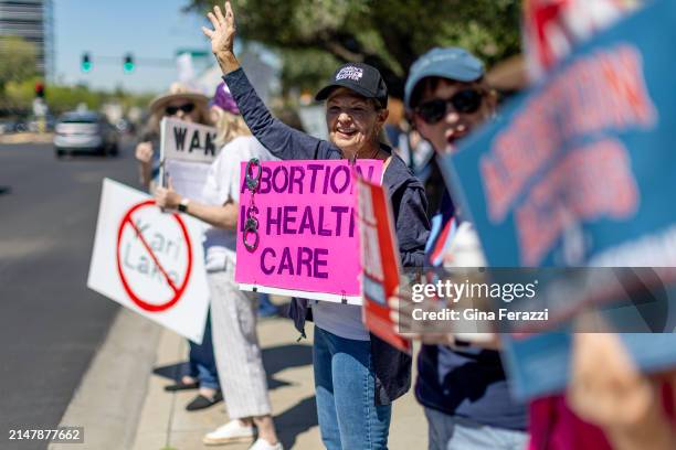 Arizona residents rally for abortion rights on a street corner Tuesday on the heels of the Arizona's Supreme Court decision enacting an 1864 law...