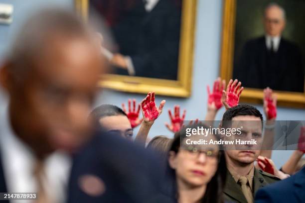 Protesters from the group Code Pink hold up painted hands as U.S. Secretary of Defense Lloyd Austin speaks at a House Appropriations Committee...