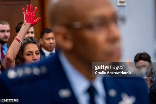 Protester with the group Code Pink holds up a painted hand as Chairman of the Joint Chiefs of Staff General Charles Q. Brown, Jr., speaks at a House...