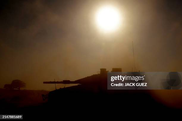 This picture taken from Israel's southern border with the Gaza Strip shows an Israeli tank silhouetted against the sun as it rolls near the...