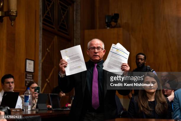 Activist Daryl Guberman holds up papers he asks chairman Sen. Richard Blumenthal to accept evidence as he interrupts a Senate Homeland Security and...