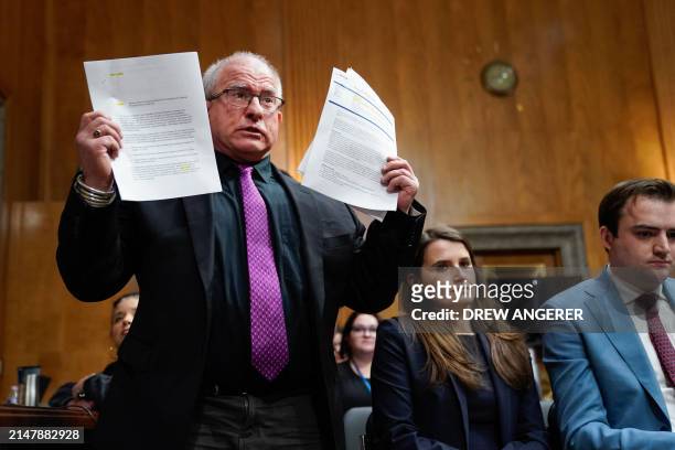 Activist Daryl Guberman holds papers and asks committee chairman Senator Richard Blumenthal to accept documents from Boeing that he wants to give to...