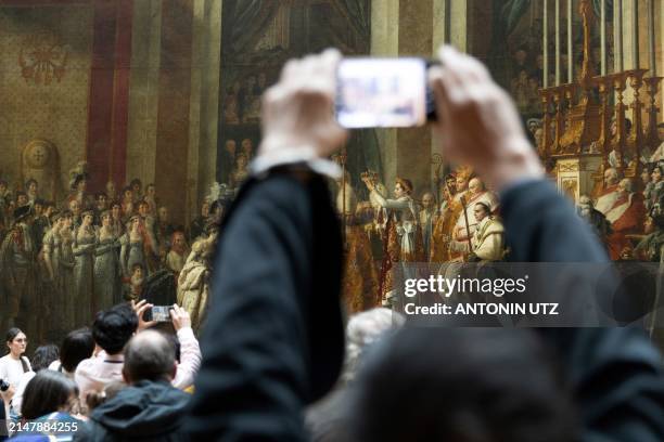 Visitor takes a picture of Jacques-Louis David's The Consecration of the Emperor Napoleon and the Coronation of the Empress Josephine in Notre-Dame...