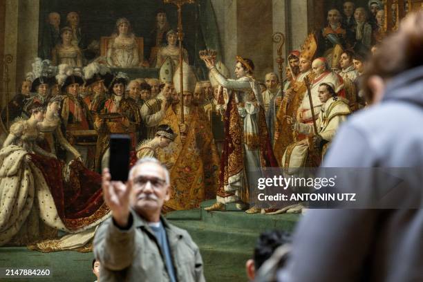 Visitor takes a selfie in front of Jacques-Louis David's The Consecration of the Emperor Napoleon and the Coronation of the Empress Josephine in...
