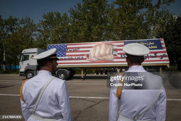 Two members of the Iranian navy are standing at attention as a truck carries a massive anti-U.S. Billboard during a military parade marking Iran's...